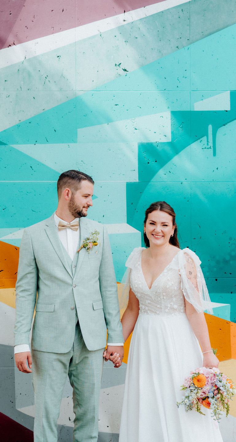 Lachendes Brautpaar bei Hochzeit in Bielefeld vor bunter Wand 